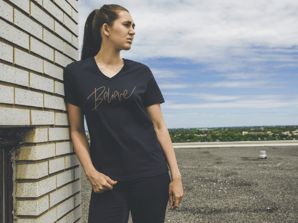 Femme portant un t-shirt ethica avec une impression sur le t-shirt mentionnant Believe